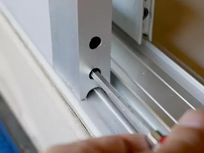 Specialist repairing a sliding glass door track and roller mechanism