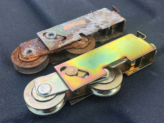 Worn sliding door roller beside a new replacement roller